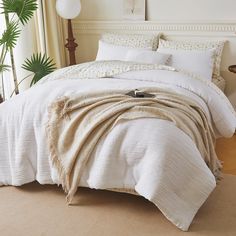 a bed with white sheets and pillows in a bedroom