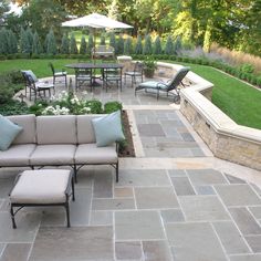 an outdoor seating area with patio furniture and landscaping in the back ground, surrounded by greenery