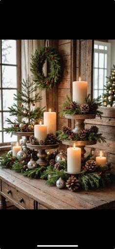 christmas candles are arranged on a table with pine cones and evergreens in the center