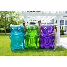 three people sitting on inflatable teddy bears with their faces painted purple, green and blue