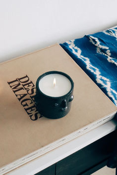 a lit candle sitting on top of a book next to a blue and white blanket