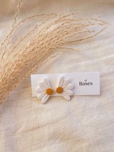 a white flower brooch sitting on top of a bed next to some dry grass