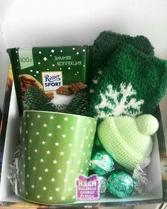 a box filled with green items including a hat, mittens and coffee mugs