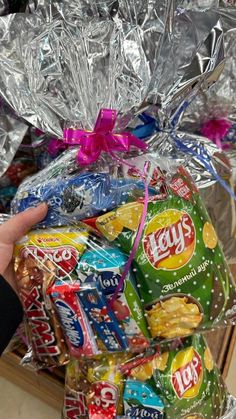 a person holding a bag full of candy and wrapped in tin foil with pink ribbon