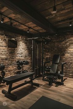 a home gym with benches, weights and dumbbells in front of a brick wall