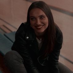 a woman sitting on a bench smiling at the camera