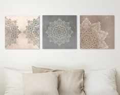 three canvases on the wall above a bed with pillows and throw pillows in front of them