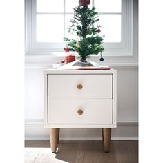 a small christmas tree sitting on top of a white dresser