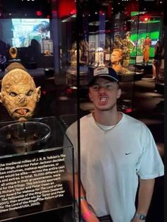 a man standing in front of a glass case with a mask on it's head