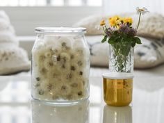 a vase filled with flowers sitting on top of a table next to a glass jar