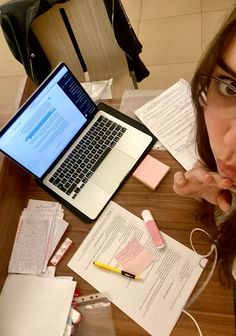 a young woman sitting at a table with her laptop and papers on the desk next to her