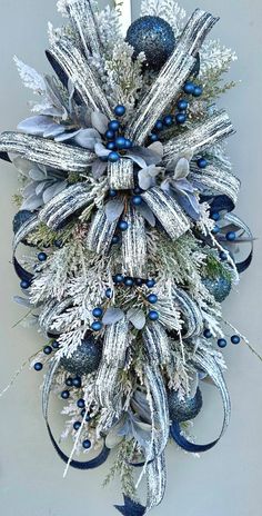 a blue and silver wreath hanging on the side of a door with snowflakes