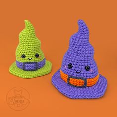 two crocheted witches hats sitting next to each other on an orange background,