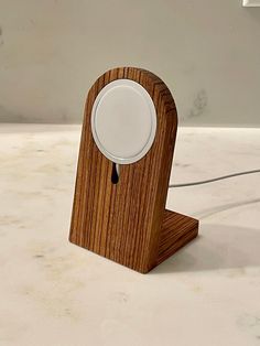 a wooden clock with a white knob on it's face sitting on a table