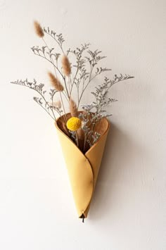 a vase with dried flowers in it hanging on the wall next to a white wall