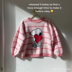 a pink and white striped sweater with a heart on it hanging from a clothes hook