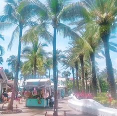 people are walking around in front of some palm trees and food carts on the street