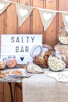 a variety of snacks are displayed on a table in front of a sign that says salty bar