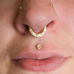 a woman's nose with gold piercings on it