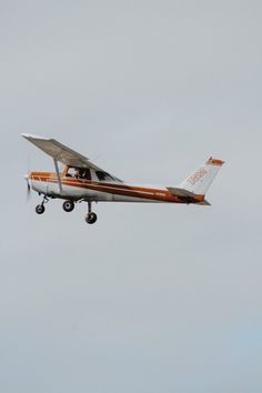 an orange and white plane flying in the sky