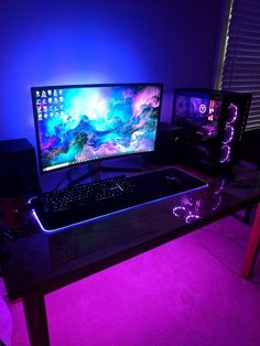 a desk with two monitors and a keyboard on it in front of a purple light