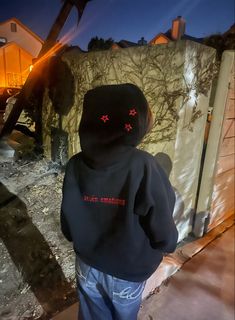 a young child wearing a black hoodie with red crosses on it's face