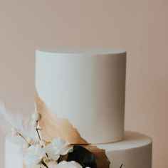 a white wedding cake with flowers and feathers