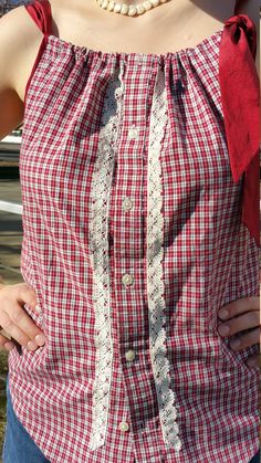 a woman wearing a red and white shirt with lace on the bottom, holding her hands in her pockets