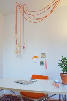 an orange chair sits in front of a white table with two laptops on it