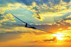 an airplane flying in the sky at sunset