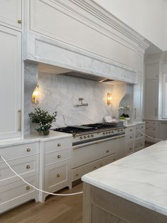 a large kitchen with white cabinets and marble counter tops, along with an island in the middle