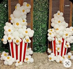 two red and white popcorn buckets filled with balloons