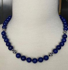 This gorgeous necklace of round lapis lazuli beads with sapphire and white gold accents is the epitome of style and sophistication! 10mm round, beautifully matched lapis with their high-polish and stunning royal blue color have been arranged with 18k white gold rondels, faceted blue sapphire beads and white gold rondels. The larger white gold rondels are set with tiny sparkling sapphires that complement the lapis perfectly, and the white gold accents have a lovely stardust finish, treating your eyes to a wonderful combination of sizes, shapes, color and textures. Hand strung on silk thread and finished with a 14k white gold clasp, this necklace is a great way to show off your sense of style and that undefinable look of understated, effortless elegance! Necklace measures 19 inches in length Royal Blue Lapis Lazuli Necklaces With Round Beads, Royal Blue Lapis Lazuli Necklace With Round Beads, Sapphire-colored Lapis Lazuli Round Beaded Jewelry, Sapphire Colored Lapis Lazuli Round Bead Jewelry, Necklace With 8mm Round Lapis Lazuli Beads, Round Lapis Lazuli Necklace With Polished Beads, Lapis Lazuli Necklace With Polished Round Beads, Luxury Blue Beaded Necklace With Polished Beads, Lapis Lazuli Round Beaded Necklaces