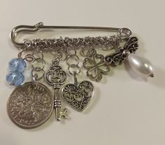 This is a gift for the Bride or Bride to be.  A classic style kilt pin or brooch in silver with charms.  The kilt pin is 2 1/4 x 2 inches.  The charms include a light blue crystal bead dangle, a silver sixpence coin, a key charm, a heart charm, a shamrock charm and a pearl bead angel.  Wear as a lapel pin before the wedding or pin onto your bouquet and carry with you on your special day. Kilt Pins, Beaded Angels, Gift For The Bride, Kilt Pin, Coin Bracelet, Turquoise Earrings Dangle, Before The Wedding, Couple Items, Lovely Earrings