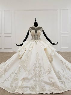 a wedding dress on display in a room with white walls and floor to ceiling windows