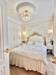 a white bed sitting in a bedroom next to a doorway with a chandelier above it