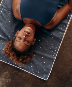 a woman laying on top of a blue mat with her eyes closed and nose piercings