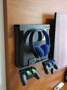 two video game controllers are hanging on the wall next to an xbox controller holder with headphones