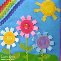 a close up of a piece of art with flowers on the side and a rainbow in the background