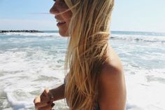 a woman standing on top of a beach next to the ocean