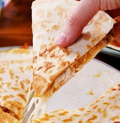 a person cutting into a piece of pizza on a plate