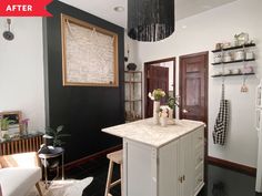 a kitchen with black walls and white cabinets, an island in the middle is decorated with flowers