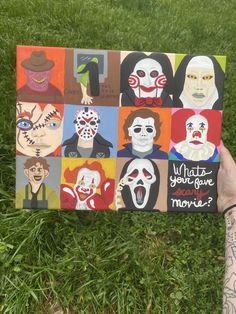 someone holding up a card with the faces of clowns on it in front of some grass