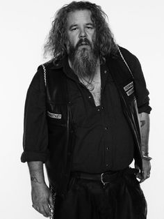 a man with long hair and beard standing in front of a white background