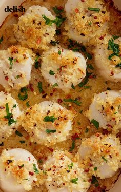 some food is in a white bowl on top of a wooden table and there are herbs sprinkled all over it