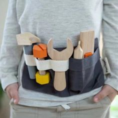 a person holding a tool belt with tools in it's pockets and the back pocket is made out of wood