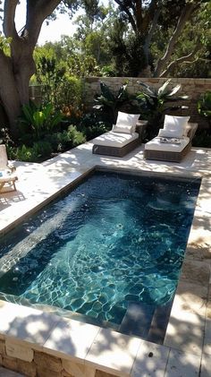 an outdoor swimming pool with lounge chairs and trees in the backgroung area