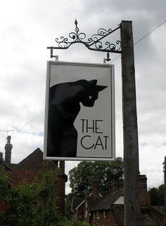 a black cat sign hanging off the side of a building