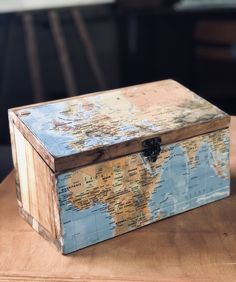 a wooden box sitting on top of a table with a world map painted on it