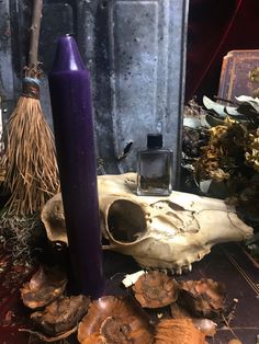 a purple candle sitting on top of a table next to some mushrooms and other items